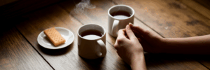 Intertwined hands next to tea mugs.